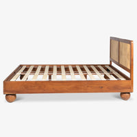 Side view of natural wooden bed with woven headboard and slatted platform