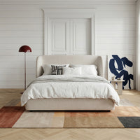 Light grey upholstered bed styled in a modern bedroom interior