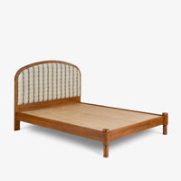 Angled view of wooden bed with curved cane headboard and natural wood frame