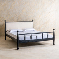 Front angled view of black metal platform bed with classic spindle headboard and wooden-style legs