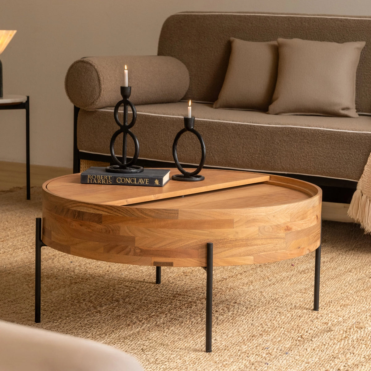 Round wooden coffee table with black metal legs in a modern living room