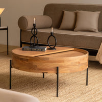 Round wooden coffee table with black metal legs in a modern living room