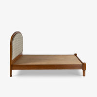 Side view of wooden bed with woven cane headboard and sturdy wooden platform