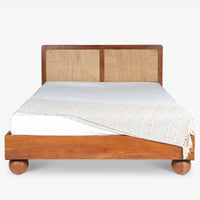 Front view of natural wooden bed with textured woven headboard and white bedding