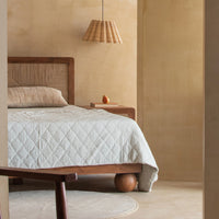 Natural wood bed with woven headboard styled in a modern bedroom interior