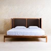 Front view of modern wooden bed with upholstered woven headboard and white bedding