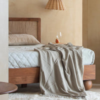 Wooden bed with textured headboard and soft white bedding in a cozy bedroom