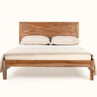Front view of wooden bed with handcrafted natural wood headboard and sturdy wooden legs