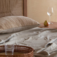 Close-up of wooden bed with quilted bedding and woven headboard detail