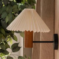 Modern cream pleated wall sconce with wooden base and indoor plants