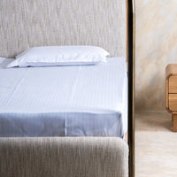 Side view of modern canopy bed with curved metal frame and upholstered mattress
