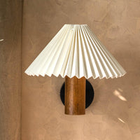 Close-up of pleated cream lampshade and wooden wall light fixture