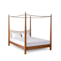 Angled view of wooden four-poster canopy bed with white mattress and classic frame