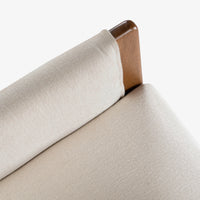 Close-up of cream fabric chair backrest and wooden armrest