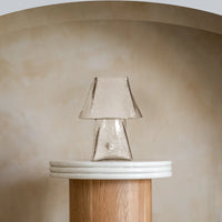 Transparent glass table lamp styled on a wooden side table in a modern interior