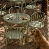 Modern green outdoor round table with metal legs in a scenic garden setting